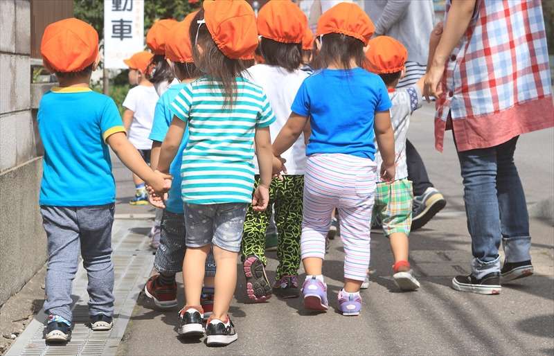 オレンジ色の帽子をかぶった園児たちの散歩